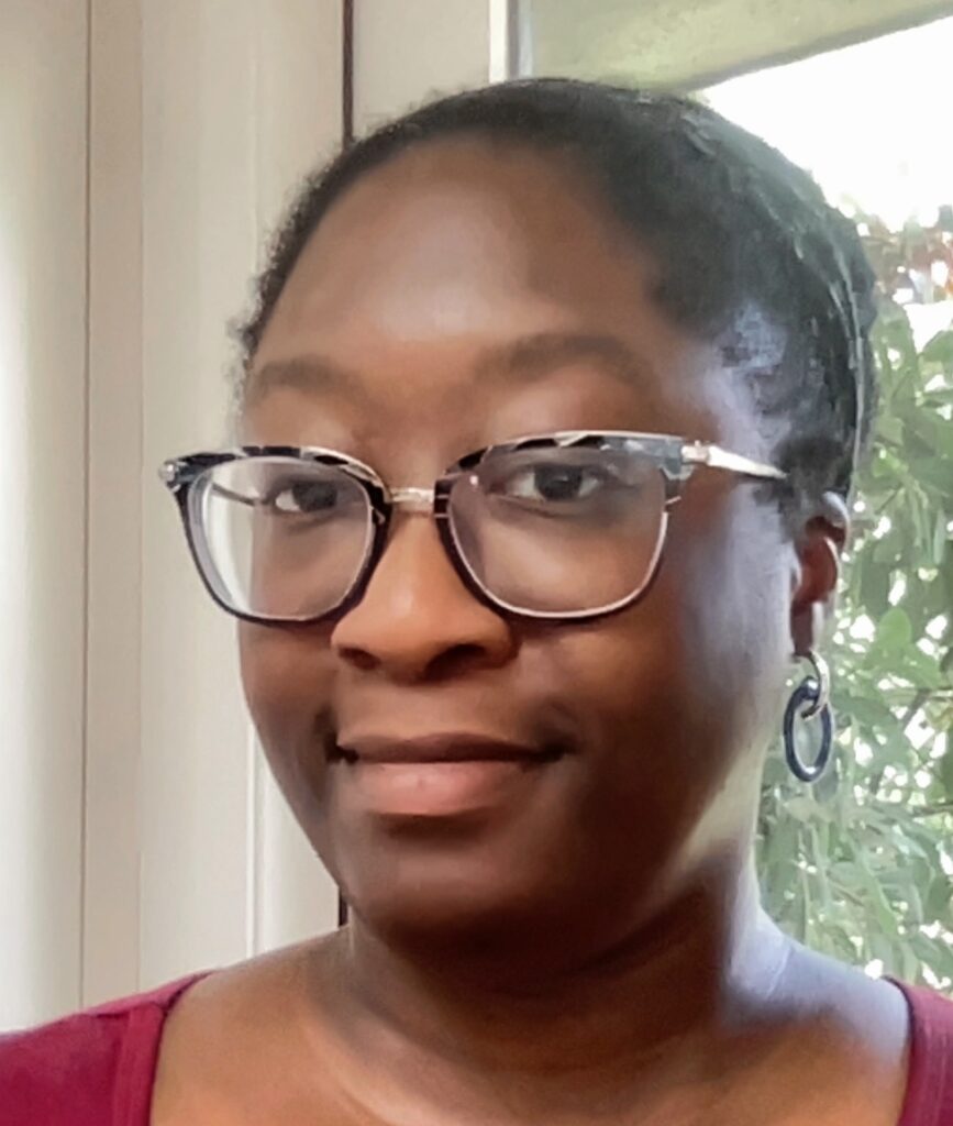 A photo of Esinam Bediako. She is wearing glasses and a red shirt.
