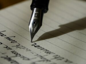 Photo of a fountain pen writing in cursive on lined paper