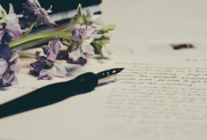 A fountain pen and purple flowers on a piece of paper